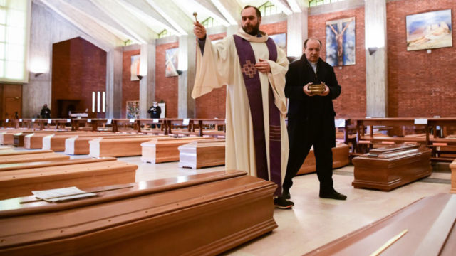 Priest Don Marcello gives a blessing to the coffins of deceased people inside the church of San Giuseppe in Seriate, on March 28, 2020. Piero CRUCIATTI / AFP