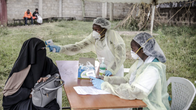 Health personnel measure the temperature of a visitor at the entrance of the Mbagathi Hospital in Nairobi, Kenya 